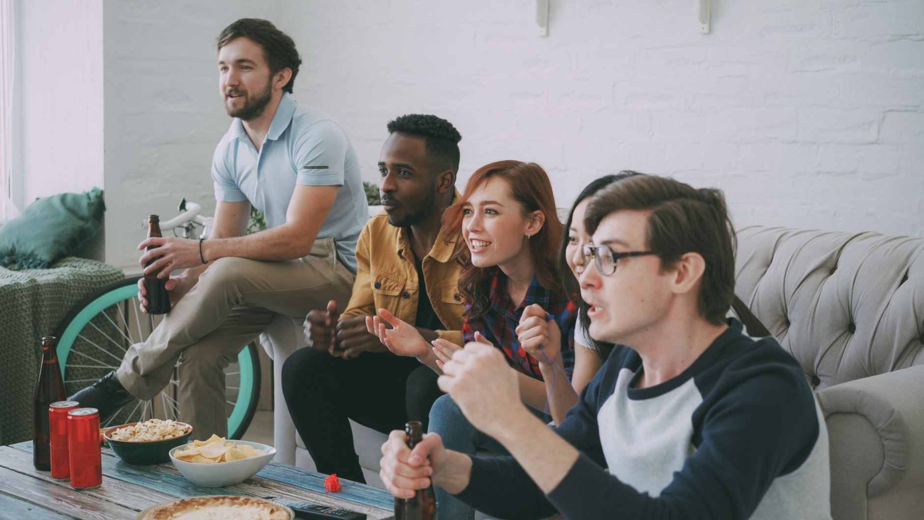Group of friends watching television together on a couch at home