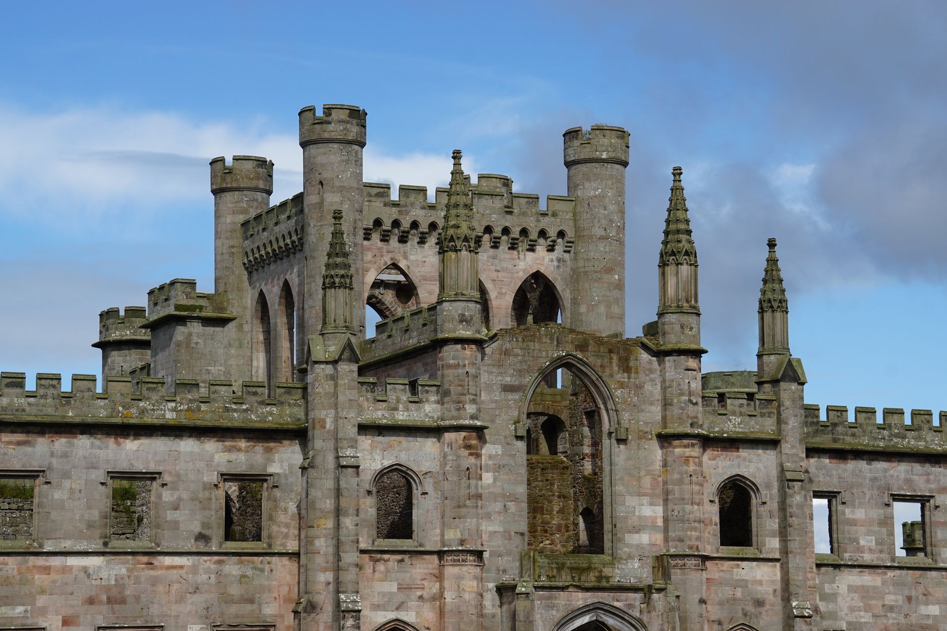 Ruined medieval castle towers and battlements against a blue sky