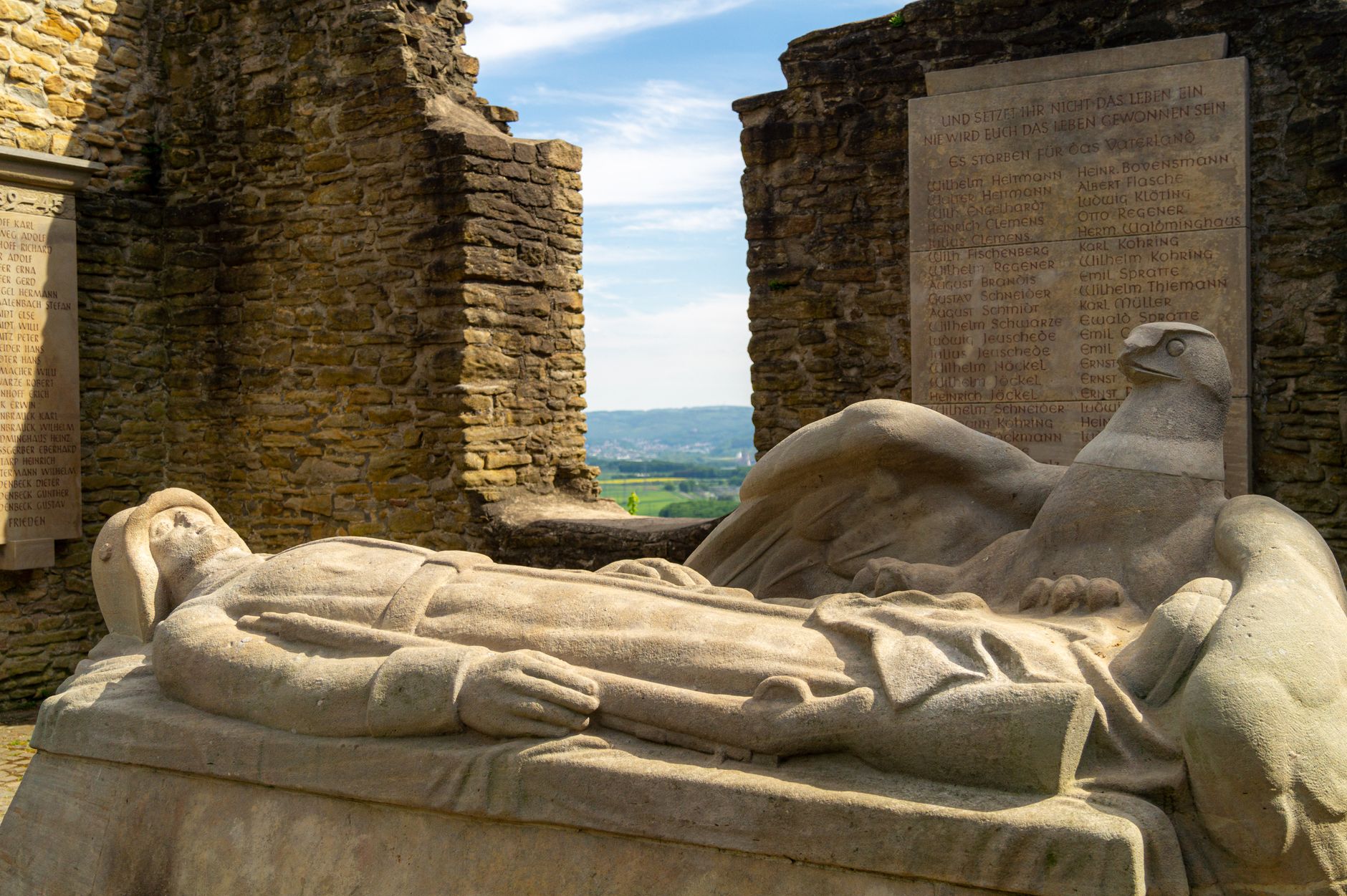 Stone war memorial with an eagle statue and inscribed names of the fallen