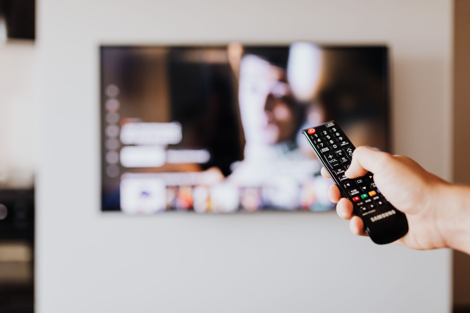 Person holding a remote control while streaming a show on TV