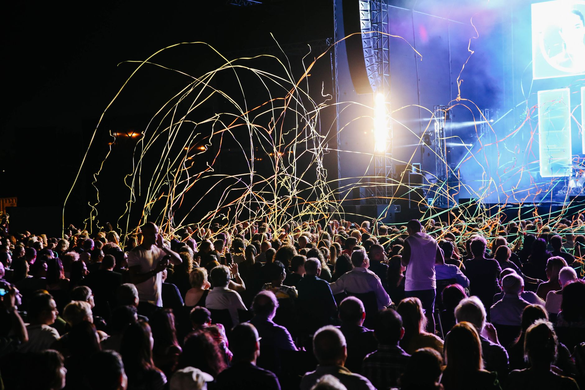 Concert crowd cheering with light sticks raised in the air
