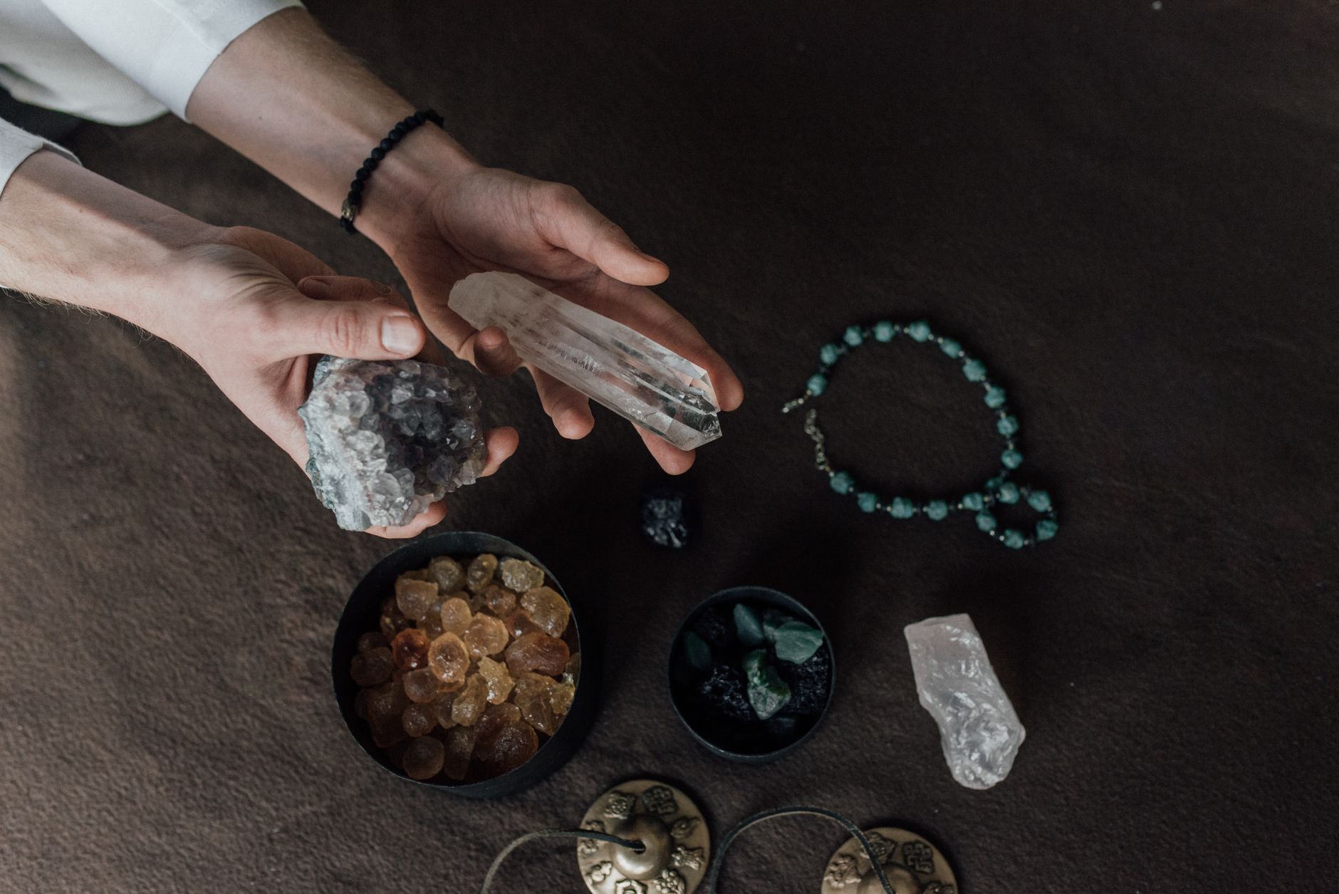 Hands holding clear quartz and amethyst crystals used in aura and energy healing practices