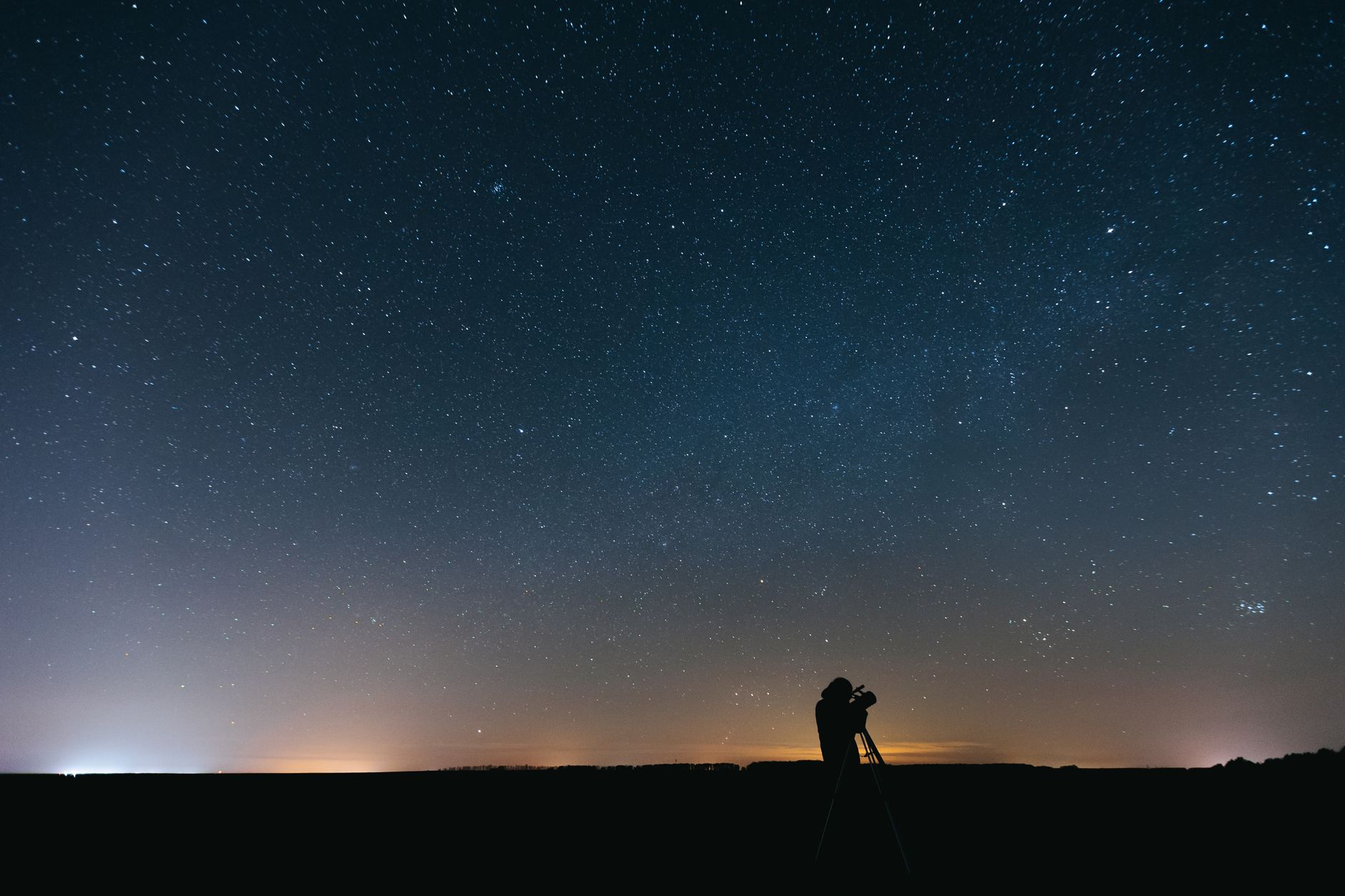 An astronomer stargazing with a telescope at night, observing the planets